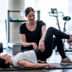 Physiotherapist helping women doing exercise