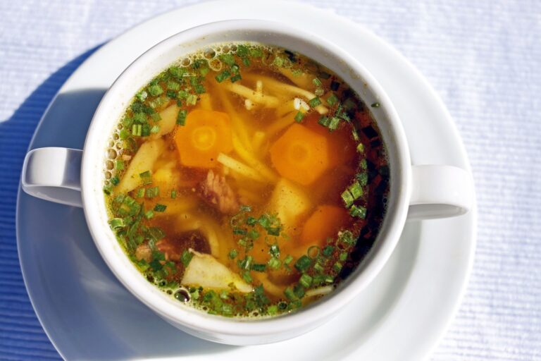 A warm cup of homemade chicken noodle soup with carrots and herbs